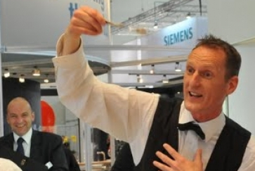 Das Zauberkunststück Gabelverbiegen auf der Standparty während der Messe